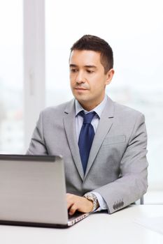 business, people and technology concept - smiling businessman in suit working with laptop computer in office