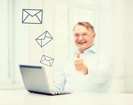 technology, oldness and lifestyle concept - old man in eyeglasses with laptop computer at home showing thumbs up