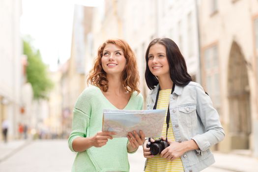 tourism, travel, leisure, holidays and friendship concept - smiling teenage girls with map and camera outdoors