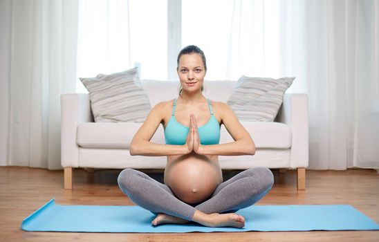 pregnancy, sport, yoga, people and healthy lifestyle concept - happy pregnant woman meditating at home