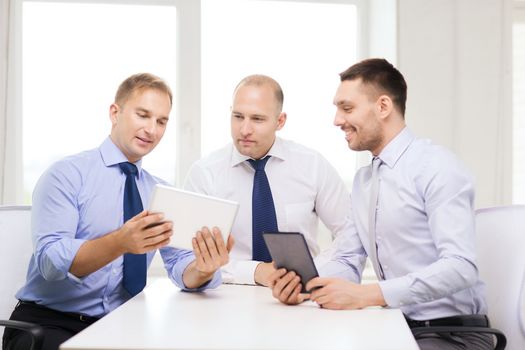 business, technology and office concept - three smiling businessmen with tablet pc computers in office