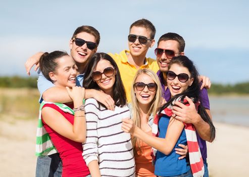 summer holidays, vacation, tourism, travel and people concept - group of happy friends having fun and hugging on beach