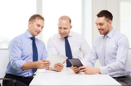 business, technology and office concept - three smiling businessmen with tablet pc computers in office