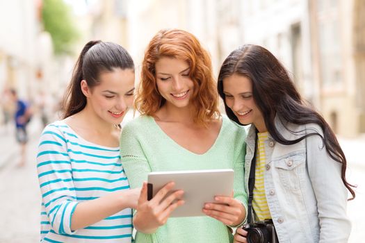 tourism, travel, leisure, holidays and friendship concept - smiling teenage girls with witch tablet pc computer and camera outdoors