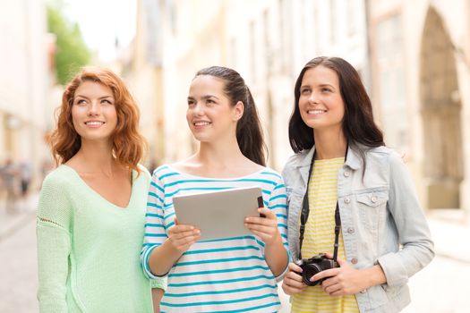 tourism, travel, leisure, holidays and friendship concept - smiling teenage girls with witch tablet pc computer and camera outdoors