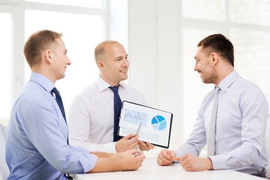 business and office concept - smiling businessman showing others charts in office