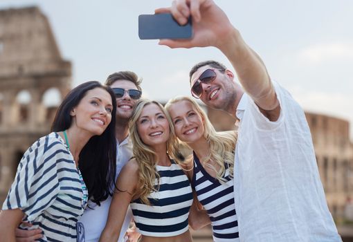 summer, europe, tourism, technology and people concept - group of smiling friends taking selfie with smartphone over coliseum background