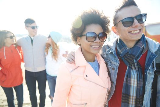 tourism, travel, people, leisure and teenage concept - group of smiling teenagers in sunglasses hugging on city street