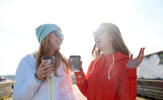 people, leisure, friendship, communication and takeaway drinks concept - happy teenage girls with coffee cups on city street