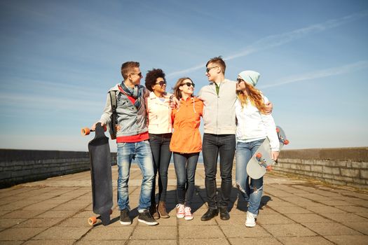 people, leisure and sport concept - group of happy teenage friends with longboards talking on city street