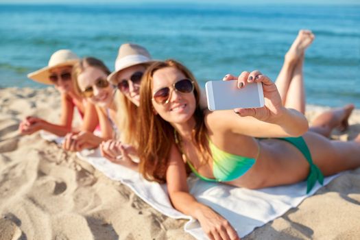 summer vacation, travel, technology and people concept - close up of smiling women in sunglasses and hats making selfie with smartphone on beach