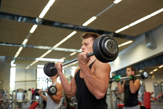 sport, bodybuilding, lifestyle and people concept - young men with barbells flexing muscles in gym