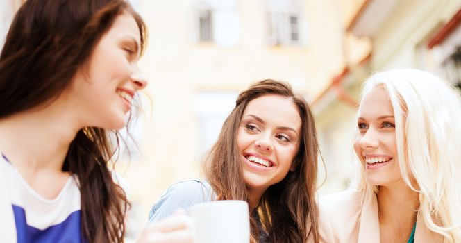 holidays and tourism concept - beautiful girls drinking coffee in cafe