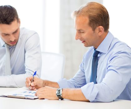 businessmen with notebook discussing graphs on meeting