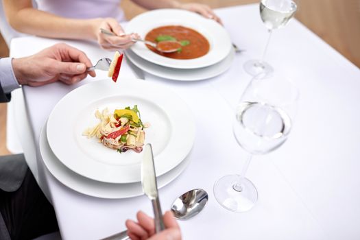 restaurant, food, people, date and holiday concept - close up of couple eating appetizers at restaurant