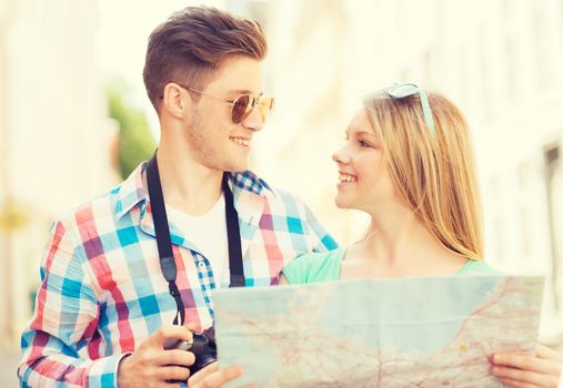 travel, vacation, technology and friendship concept - smiling couple with map and photo camera exploring city