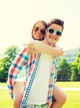 holidays, vacation, love and friendship concept - smiling couple having fun in park