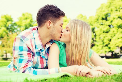 holidays, vacation, love and friendship concept - smiling couple kissing in park