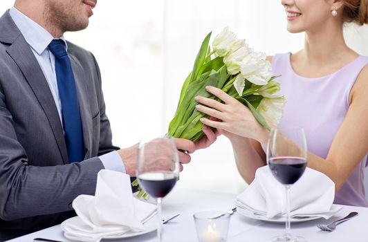 restaurant, people, celebration and holiday concept - smiling young couple with glasses of red wine looking at each other at restaurant