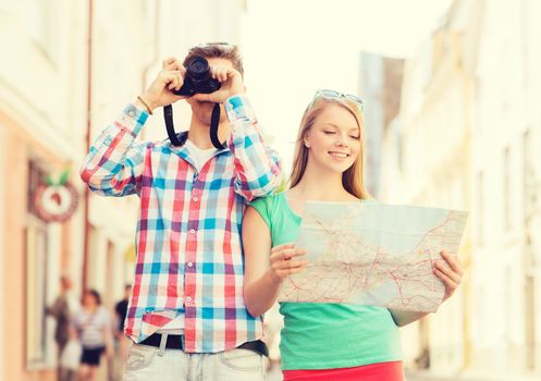 travel, vacation, technology and friendship concept - smiling couple with map and photo camera exploring city