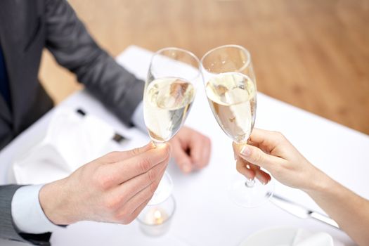 restaurant, people, celebration and holiday concept - close up of happy couple with glasses of champagne at restaurant