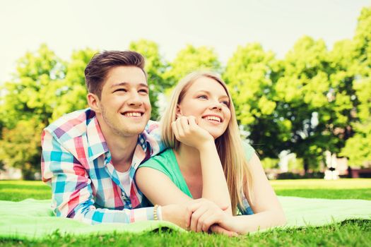 holidays, vacation, love and friendship concept - smiling couple lying on blanket in park