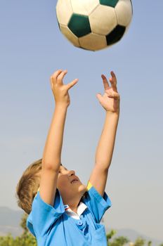 Little football player catches a ball arms, which is highly threw his father