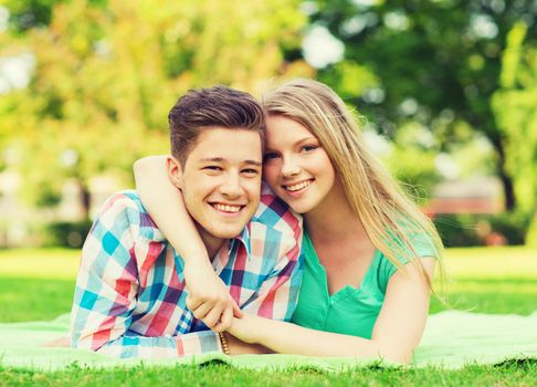 holidays, vacation, love and friendship concept - smiling couple lying on blanket in park