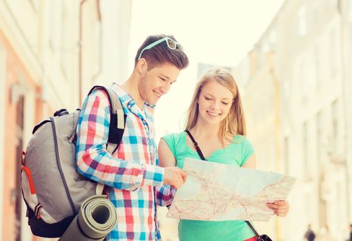 travel, vacation and friendship concept - smiling couple with map and backpack in city