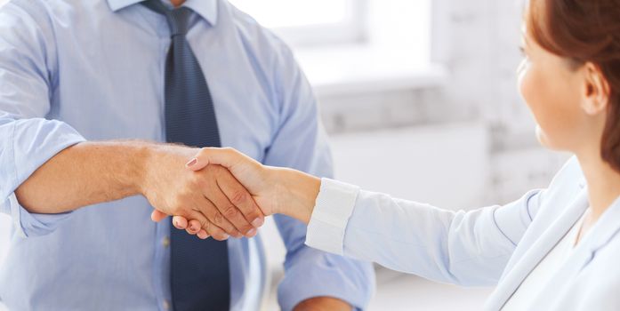 businesss and office concept - businessman and businesswoman shaking hands in office