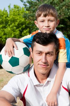 Father and son came to the park to play football and take a picture