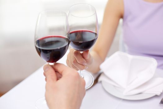 restaurant, people, celebration and holiday concept - close up of young couple with glasses of red wine at restaurant