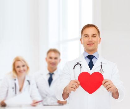 medicine, profession, charity and healthcare concept - smiling male doctor with red heart and stethoscope over group of medics