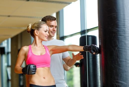 sport, fitness, lifestyle and people concept - smiling woman with personal trainer boxing in gym