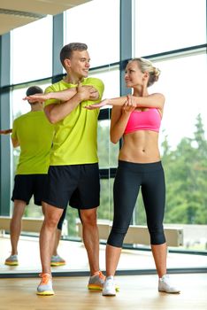 sport, fitness, lifestyle and people concept - smiling man and woman stretching in gym