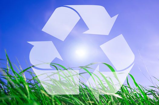 Environment conceptual image. Recycling sign against the grass and blue sky.