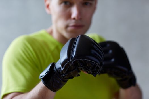 sport, competition, strength and people concept - young man in fighting or boxing position over concrete wall background