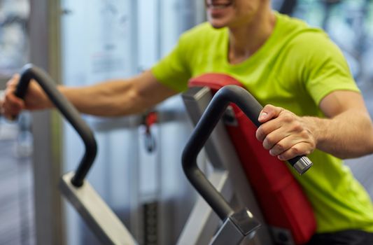 sport, fitness, lifestyle and people concept - close up of smiling man exercising on gym machine