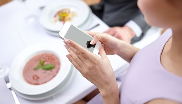 people, leisure, eating and technology concept - close up of couple with smartphones taking picture of food at restaurant