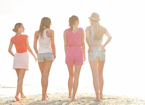 summer vacation, holidays, travel, friendship and people concept - group of young women walking on beach