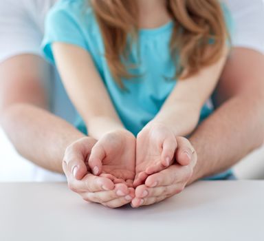 people, charity, family and advertisement concept - close up of father and girl holding something in empty cupped hands at home