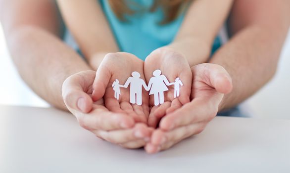 people, charity and happiness concept - close up of father and girl holding paper family cutout in cupped hands at home