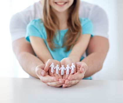 people, charity, demography and family concept - close up of father and girl holding cutout human in cupped hands at home