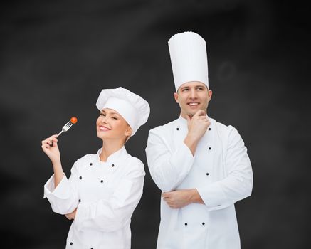 cooking, profession, inspiration and people concept - happy male chef cook thinking over black chalk board background