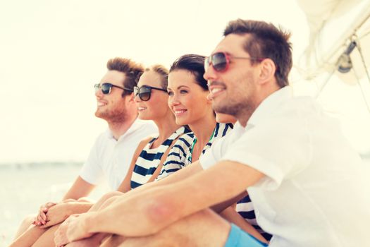 vacation, travel, sea, friendship and people concept - smiling friends sitting on yacht deck