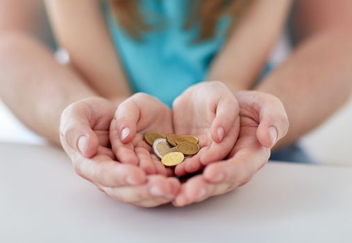 family, children, money, investments and people concept - close up of father and daughter hands holding euro money coins