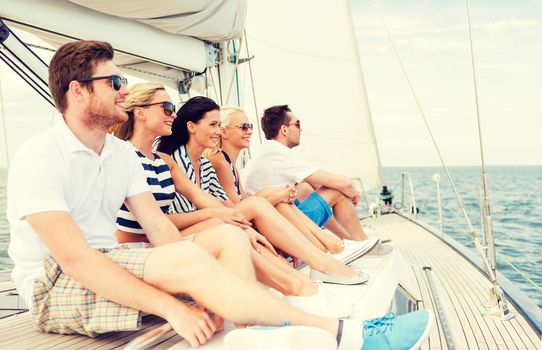 vacation, travel, sea, friendship and people concept - smiling friends sitting on yacht deck