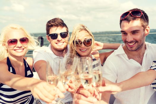 vacation, travel, sea, friendship and people concept - smiling friends with glasses of champagne on yacht