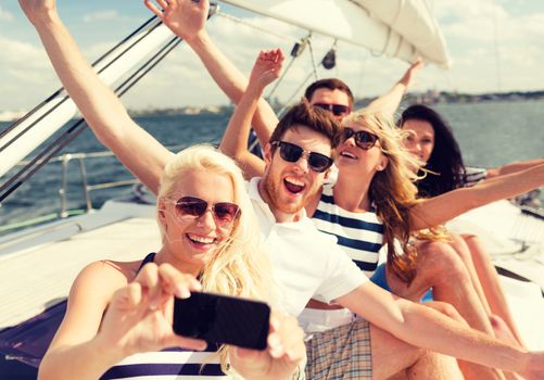 vacation, travel, sea, friendship and people concept - smiling friends sitting on yacht deck and making selfie