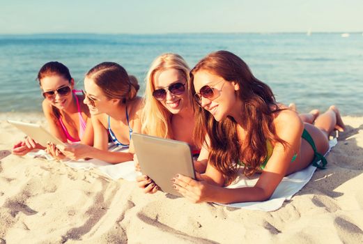 summer vacation, travel, technology and people concept - group of smiling women in sunglasses with tablet pc computers lying on beach